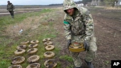 FILE - An interior ministry sapper collects mines on a mine field after recent battles in Irpin close to Kyiv, Ukraine, April 19, 2022. 