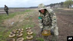 FILE - An interior ministry sapper collects mines on a mine field after recent battles in Irpin close to Kyiv, Ukraine, April 19, 2022. 