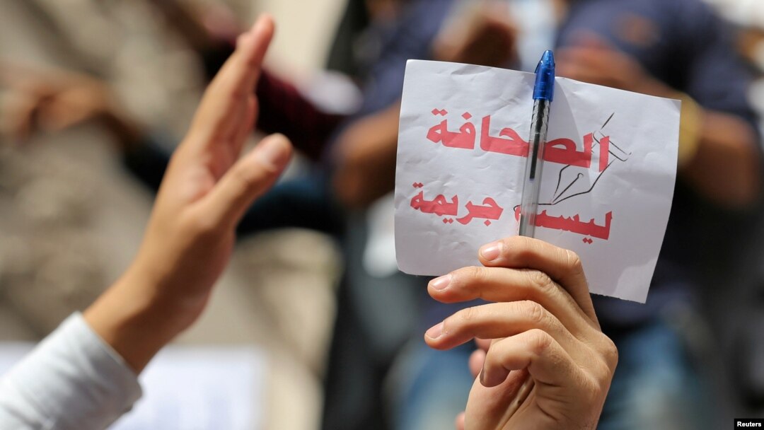 Para wartawan menmgacungkan kertas bertuslikan "jurnalisme bukanlah kejahatan" dalam aksi protes terkait kebebasan pers di Kairo, Mesir, pada 4 Mei 2016. (Foto: Reuters/Staff)