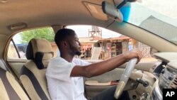 FILE: Adenekan Ayomide, 27, an undergraduate student turned a taxi driver following nationwide university strike, poses for a photograph inside his taxi in Abuja, Nigeria. Taken 5.10.2022