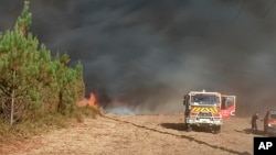 FILE - Photo provided by the fire brigade of the Gironde region SDIS 33, shows smoke and flames consuming trees at a forest in Saint Magne, south of Bordeaux, Aug. 10, 2022.