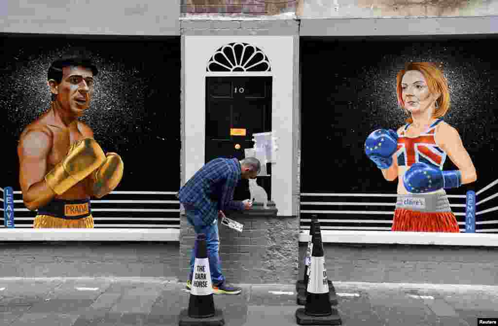 Artist Ciaran Gallagher finishes his mural depicting Britain&#39;s Conservative leadership candidate Rishi Sunak and British Foreign Secretary and Conservative leadership candidate Liz Truss, by painting Larry the cat, in the city center of Belfast, Northern Ireland.