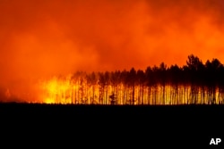 FILE - This photo provided by the fire brigade of the Gironde region SDIS 33, (Departmental fire and rescue service 33) shows a wildfire burning near Saint-Magne, south of Bordeaux, southwestern France, Aug. 12, 2022. The season of heat waves and wildfires produced excellent grapes, despite lower yields. (SDIS 33 via AP, File)