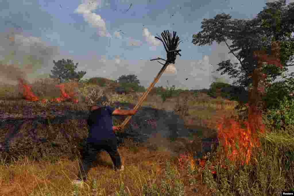 A villager attempts to put out a brush fire with a mop during a drought in Xinyao village, Nanchang city, Jiangxi province, China.
