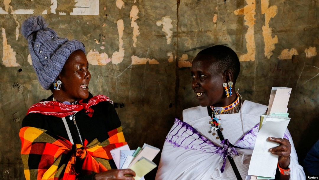 Maasai traditional women talk near a voting booth at a polling center before casting their ballots during the general election at a primary school in Kajiado county, Kenya, Aug. 9, 2022.
