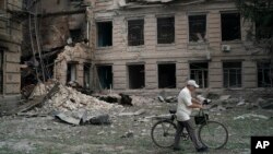 A man pushes his bicycle past a damaged technical school building after a Russian attack in Slovyansk, Ukraine, Aug. 26, 2022.