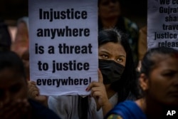 Seorang aktivis memegang plakat dalam aksi protes atas dibebaskannya 11 pelaku perkosaan beramai-ramai yang semula dihukum penjara seumur hidup, di New Delhi, India, Kamis, 18 Agustus 2022. (AP/Altaf Qadri)