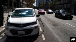 FILE — An electric vehicle is plugged into a charger in Los Angeles, Aug. 25, 2022.