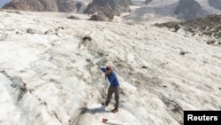 FILE - A glaciologist drills a hole at a measuring point on the Pers Glacier near the Alpine resort of Pontresina, Switzerland, July 21, 2022. 