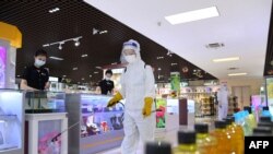 FILE - This undated picture released from North Korea's official Korean Central News Agency (KCNA) on July 2, 2022, shows a worker disinfecting to stop the spread of COVID-19 in a Pyongyang shop.