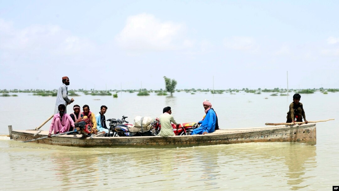 Sejumlah warga menggunakan perahu untuk menyelamatkan harta-benda dari banjir bandang yang melanda Provinsi Sindh, di selatan Pakistan, Sabtu, 27 Agustus 2022. (Foto: Pervez Masih/AP)