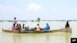 Sejumlah warga menggunakan perahu untuk menyelamatkan harta-benda dari banjir bandang yang melanda Provinsi Sindh, di selatan Pakistan, Sabtu, 27 Agustus 2022. (Foto: Pervez Masih/AP)