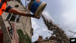 A worker cleans debris from a rocket strike on a house in Kramatorsk, Donetsk region, eastern Ukraine, Aug. 12, 2022.