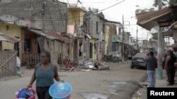 Una residente lleva sus pertenencias fuera del área de una explosión que dejó heridos y otros muertos al destruir varias casas y vehículos, según medios locales, en el sur de Guayaquil, Ecuador, 14 de agosto de 2022. REUTERS/Vicente Gaibor del Pino