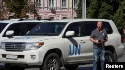 A member of International Atomic Energy Agency (IAEA) mission, expected to visit Ukraine's Zaporizhzhia nuclear power plant, stands by a U.N. vehicle near a hotel in central Kyiv, Aug. 30, 2022. 