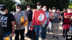 FILE - Migrants, some holding Red Cross blankets, are seen after arriving at Union Station near the U.S. Capitol from Texas on buses, in Washington, April 27, 2022.