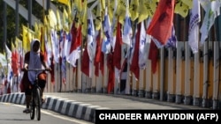 Seorang perempuan bersepeda melewati bendera partai politik jelang Pemilu 2019 di Banda Aceh, 23 Maret 2019. (Foto: AFP/CHAIDEER MAHYUDDIN)