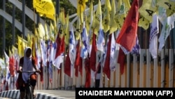 Seorang perempuan bersepeda melewati bendera partai politik jelang Pemilu 2019 di Banda Aceh, 23 Maret 2019. (Foto: AFP/CHAIDEER MAHYUDDIN)