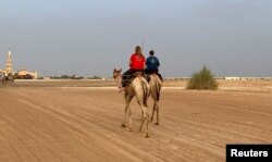 Pelatih unta Jana Schmiedel dan Michelle O'Malley berlatih menunggang unta di Arabian Desert Camel Riding center di Dubai, Uni Emirat Arab 1 Agustus 2022. (REUTERS/Abir Al Ahma)