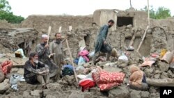 People collect their belongings from their damaged homes after heavy flooding in the Khushi district of Logar province south of Kabul, Afghanistan, Sunday, Aug. 21, 2022. 