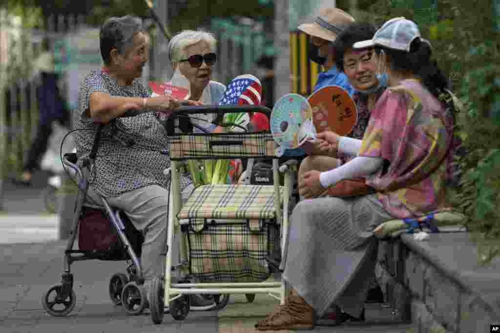 Residents fan themselves as they chat with each other outside a residential complex in Beijing, China.