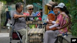 Residents fan themselves as they chat with each other outside a residential complex in Beijing, China.