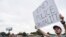 Miles Mason, 25, protests outside the sheriff's department where three Arkansas law enforcement officers have been suspended after a video circulated widely online over the weekend showing them punching and kicking a suspect.