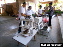 Dengan mesin sederhana dengan teknik yang tepat, Komunitas Bijak Sampah memproduksi material seperti konblok dan pembatas jalan berbahan plastik dan pasir. (Foto: VOA/Nurhadi)