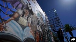 Mexican mural artist Janet Calderon paints on the facade of a municipal building in San Salvador, Mexico, July 30, 2022. 