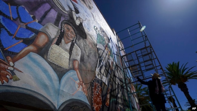 Mexican mural artist Janet Calderon paints on the facade of a municipal building in San Salvador, Mexico, July 30, 2022.