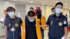 FILE - Police officers from the Taiwan Criminal Investigation Bureau escort two suspects who were deported from Bangkok and believed to be involved in scam cases in Cambodia. (Taiwan Criminal Investigation Bureau via AP)