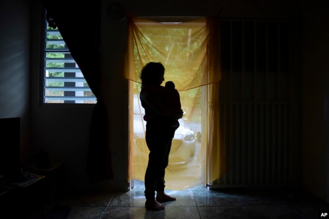 FILE - Michelle Flandez stands in her home with her two-month-old son Inti Perez, woh is diagnosed with microcephaly linked to the mosquito-borne Zika virus, in Bayamon, Puerto Rico on Dec. 16, 2016. (AP Photo/Carlos Giusti, File)
