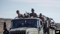 FILE - Ethiopian government soldiers ride in the back of a truck on a road near Agula, north of Mekelle, in the Tigray region of northern Ethiopia on May 8, 2021.