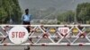 A policeman stands behind a barrier on the road leading towards the Presidency, National Assembly, Supreme Court and diplomatic enclave in Islamabad June 6, 2008. Pakistan boosted security in the capital Islamabad and neighbouring Rawalpindi on Friday whe