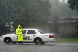 A Cameron Parish Sheriff's deputy wipes his face as he stands at a roadblock in the rain on LA 27 while residents evacuate Cameron in Lake Charles, Louisiana, August 26, 2020, ahead of Hurricane Laura.