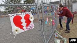 A woman and her daughter place a heart on a fence at a growing memorial in front of the Debert School in Debert, Nova Scotia, Canada, April 20, 2020. Lisa McCully, a teacher at the school, was among those killed in Sunday's shooting rampage.