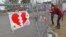 A woman and her daughter place a heart on a fence at a growing memorial in front of the Debert School in Debert, Nova Scotia, Canada, April 20, 2020. Lisa McCully, a teacher at the school, was among those killed in Sunday's shooting rampage.
