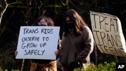 ARCHIVO - Dos personas muestran letreros a los automóviles que pasan durante una manifestación en pro de los derechos de las personas transgénero frente al Hospital Infantil de Seattle, el domingo 9 de febrero de 2025, en Seattle. 