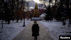 A woman walks near an illuminated Christmas tree, in Kyiv, amid Russia's attack on Ukraine, Dec. 12, 2024.