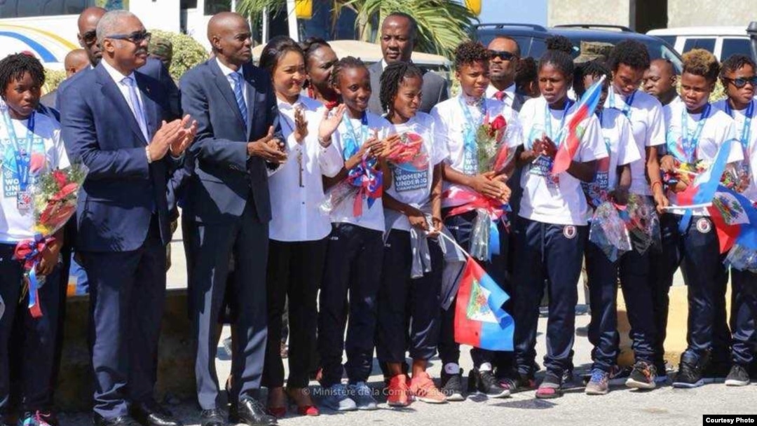 Haitian President Jovenel Moise, third from left, and Prime Minister Jacques Guy Lafontant, second from left, greet the U-20 women's team at Toussaint Louverture International Airport in Port-au-Prince with flowers, handshakes and praise for job well done, Jan. 30, 2018. (FHF photo) 