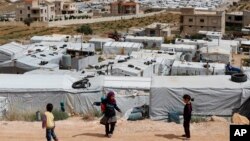 Anak-anak pengungsi Suriah bermain di dekat kamp pengungsi sementara yang dibangun di antara permukiman penduduk dan bangunan-bangunan lainnya di Arsal, perbatasan Suriah-Lebanon timur, 13 JUni 2018. (Foto: dok). 