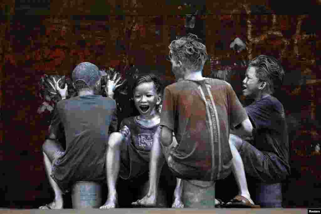 Youths, who covered themselves in silver paint to become &#39;manusia silver&#39; (silvermen) to make a living, laugh as they ride on the back of a truck in Jakarta, Indonesia.