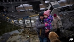 Local militiaman Valery, 37, carries a child as he helps a fleeing family across a destroyed bridge, on the outskirts of Kyiv, Ukraine, March 2. 2022. 