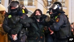 Police officers detain a woman in St. Petersburg, Russia, Feb. 25, 2022.