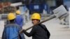 FILE - A worker walks past a road construction site in Beijing, October 15, 2015.