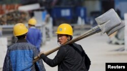 FILE - A worker walks past a road construction site in Beijing, October 15, 2015.