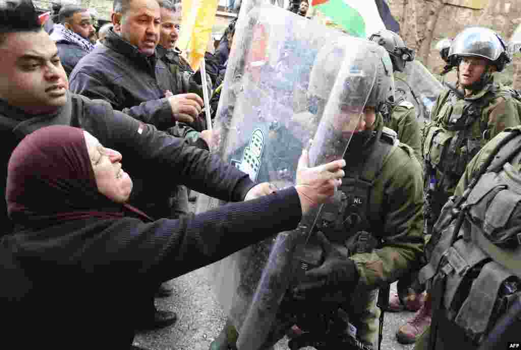 A Palestinian woman confronts members of the Israeli security forces following a demonstration to commemorate the 1994 Ibrahimi Mosque massacre, in the center of the West Bank town of Hebron.