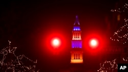 A red traffic light frames the the George Washington Masonic National Memorial which is lit with blue and yellow lights in support of Ukraine, in Alexandria, Va., Feb. 26, 2022.