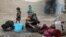 FILE - An internally displaced Afghan woman washes clothes outside her shelter on the outskirts of Kabul, Afghanistan, Feb. 3, 2021. 