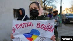 A person holds a sign that reads "We are against war" during a protest against Russian invasion of Ukraine, after President Vladimir Putin authorized a massive military operation, in Moscow, Feb. 27, 2022.